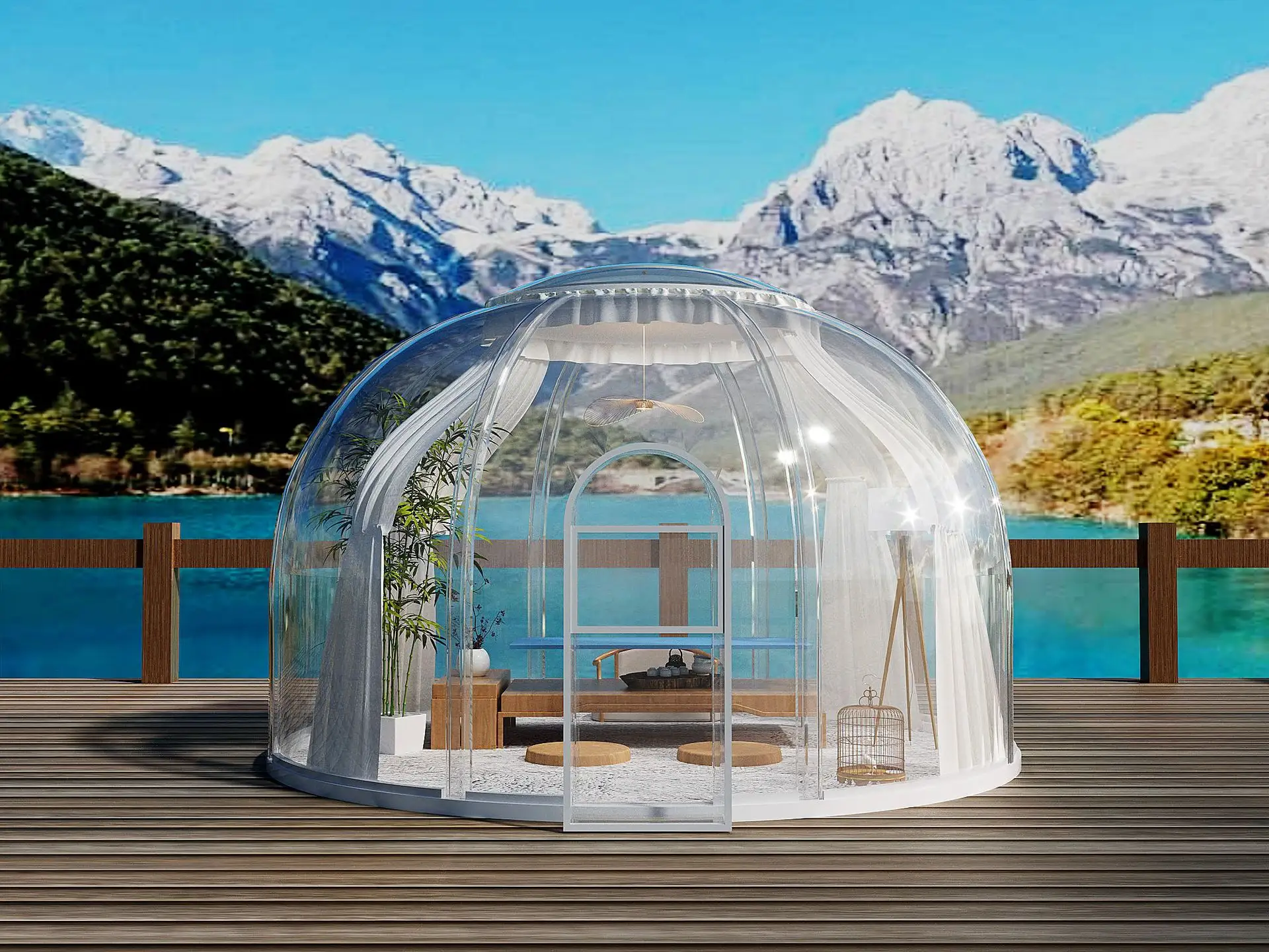 A transparent dome structure set on a wooden deck, with a small seating area inside, overlooks a lake and mountainous landscape on a clear day.