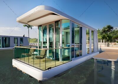 A modern, white floating house with glass walls is anchored near a tropical coastline. The house has a balcony with seating and nearby similar structures are visible in the background.