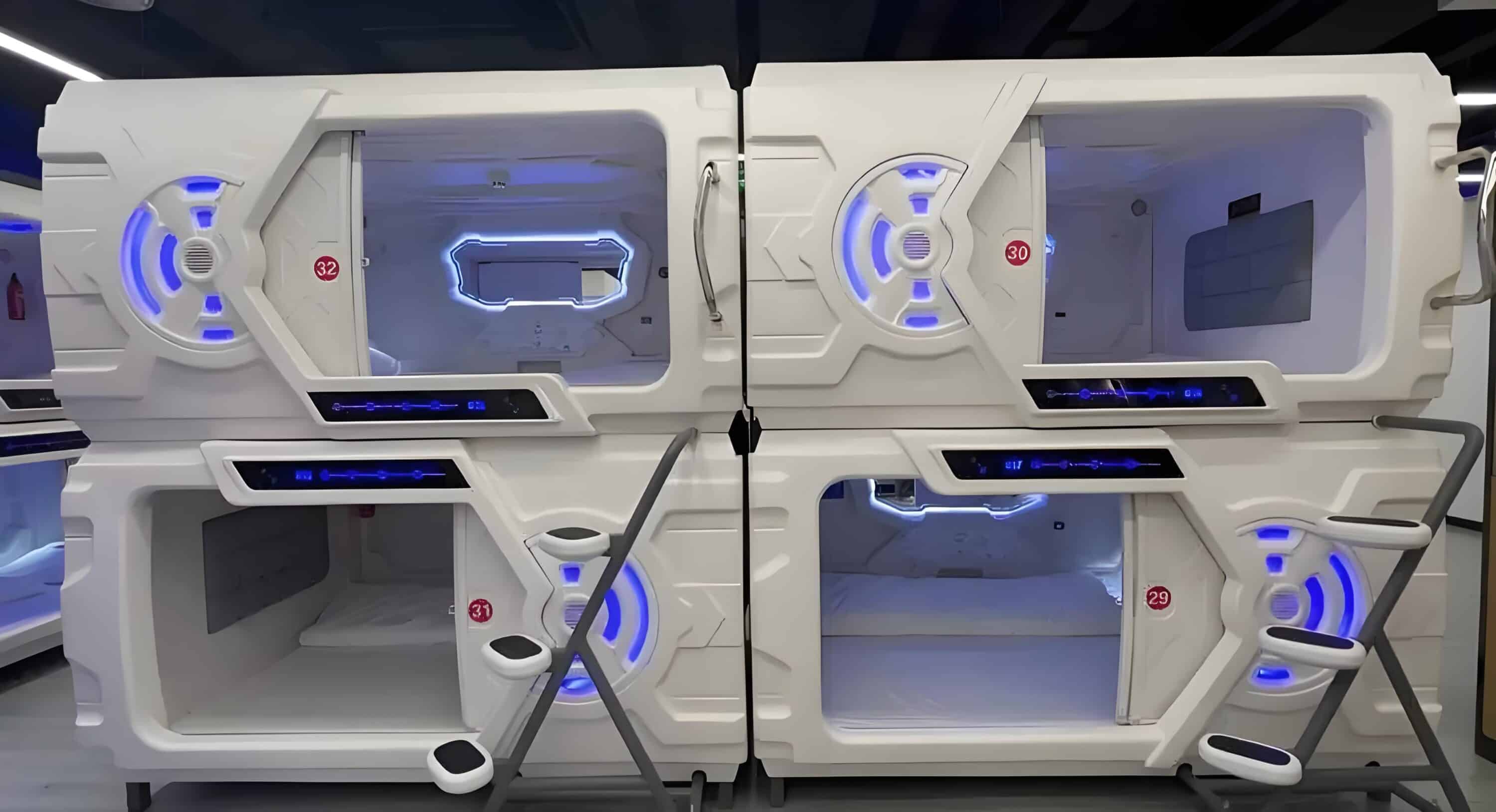 A Futuristic Capsule Hotel Pod With Blue Led Lighting, Featuring Two Stacked Sleeping Compartments, Each With A Small Ladder, Control Panel, And A Window.