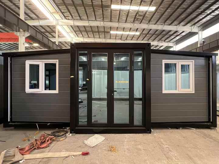 A Modular Building With Large Glass Doors And Two White Framed Windows, Situated Inside A Warehouse.