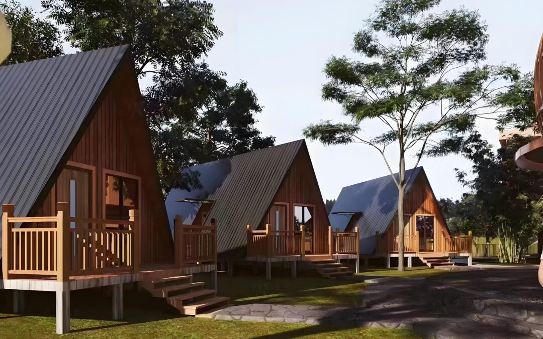 A Row Of Small, Wooden A Frame Cabins With Steps And Porches, Set Among Trees On A Grassy Area Under A Clear Sky.