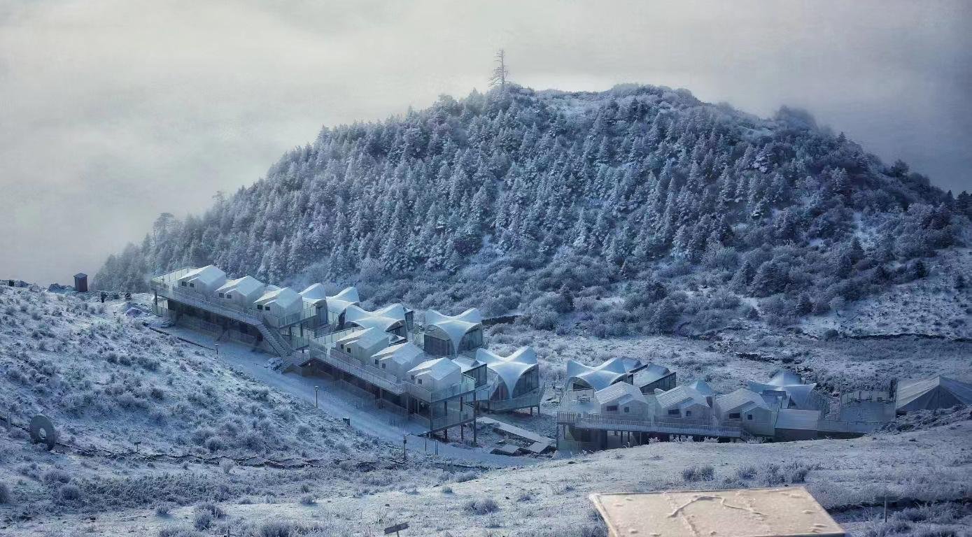 A cluster of white buildings stands at the base of a snow covered hill with dense trees under a cloudy sky.